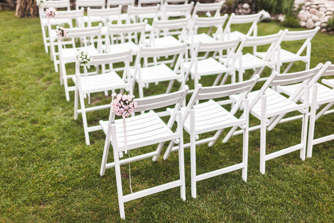 Tri-City Tent Rentals in Schenectady, NY outdoor event with white chairs and pink flowers.